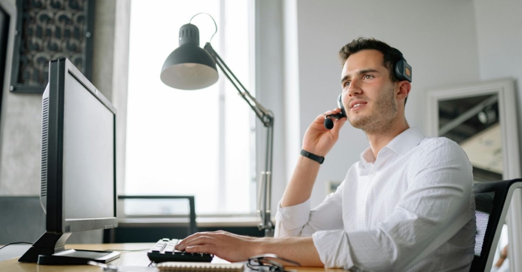 man on headset phone in front of computer