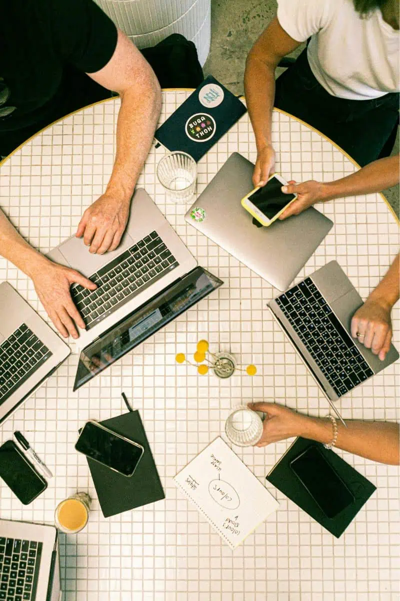 Multiple laptop and phone users at a table - business internet service